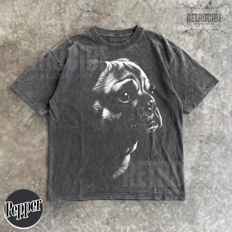 May include: A charcoal grey short-sleeve t-shirt featuring a white graphic illustration of a dog's face in profile. The fabric has a washed, faded appearance. The text "RETROCIDE" is printed in the top right corner and "Pepper" in a circle.