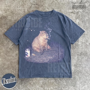 May include: A charcoal gray short-sleeve t-shirt featuring a graphic print of a capybara sitting on the ground with a lit cigarette in its mouth, smoke rising above, and a silver can of Pabst Blue Ribbon beer placed on the ground nearby.