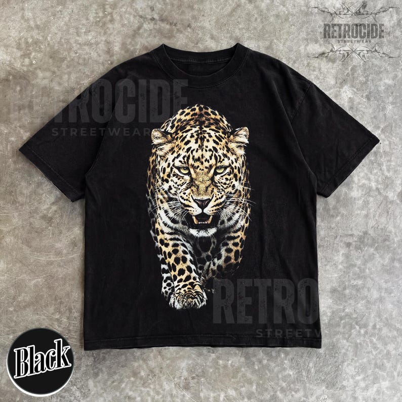 May include: Black t-shirt featuring a detailed leopard graphic. The shirt has the text "RETROCIDE STREETWEAR" printed on it. A black circle with the word "Black" is at the bottom. The shirt is made of a soft material.