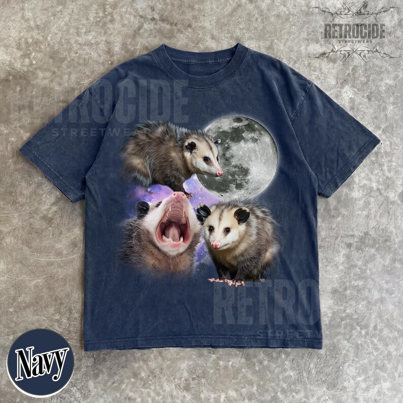 May include: Navy blue t-shirt with a graphic of three opossums, a full moon, and a purple galaxy. The opossums are in various poses, including one yawning. The shirt has a vintage, distressed appearance.