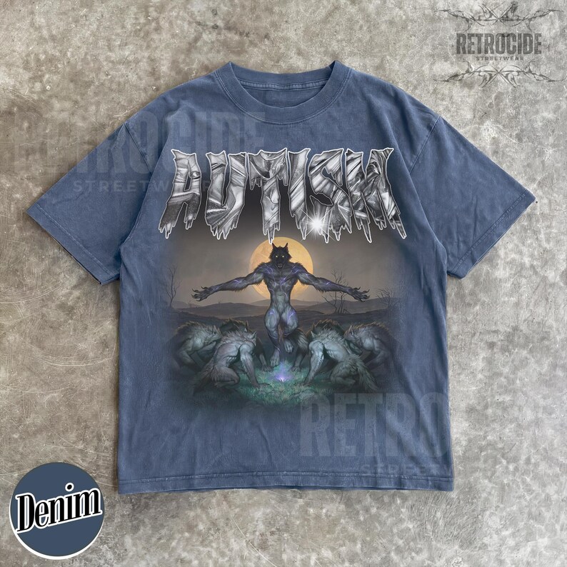 May include: A faded blue short-sleeve t-shirt featuring the text AUTISM in a metallic, jagged font at the top. Below the text is a graphic of a central werewolf figure standing with arms outstretched before a full moon, surrounded by other wolf-like creatures.