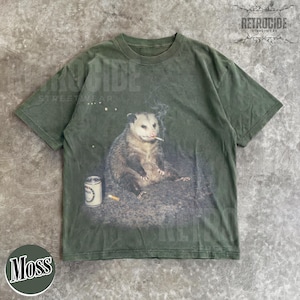 K&ouml;nnte beinhalten: Moosgr&uuml;nes T-Shirt mit einem Aufdruck eines Opossums, das eine Zigarette raucht, mit einer Bierdose und einem Zigarettenstummel. Das Shirt hat einen Vintage-Look mit dem Text "RETROCIDE STREETWEAR" oben rechts.
