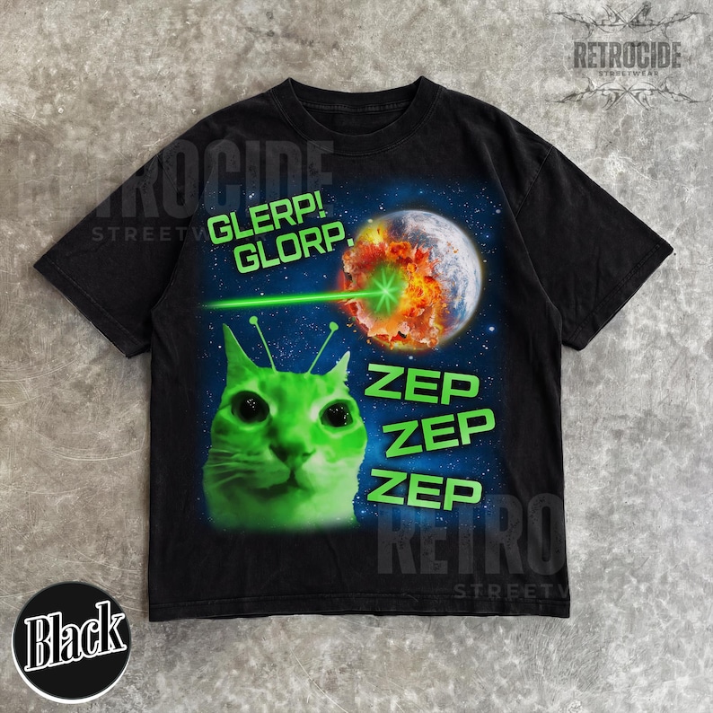 May include: Black t-shirt featuring a green alien cat with antennae, a laser beam, and a planet being destroyed. Text includes "GLERP! GLORP." and "ZEP ZEP ZEP." The shirt has a retro streetwear design.