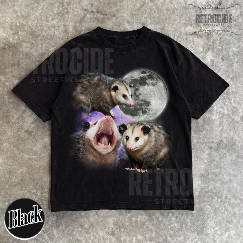 May include: Black t-shirt with a graphic of three opossums and a full moon. The opossums are in different poses, one yawning. The shirt has the text "RETROCIDE STREETWEAR" and "Black" on the bottom.