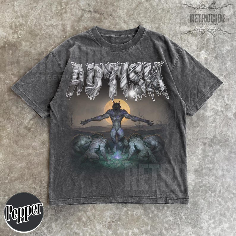 May include: A charcoal gray short-sleeve t-shirt featuring a graphic print of a central werewolf figure with arms outstretched before a full moon, surrounded by smaller wolf-like creatures. The word AUTISM is printed in a metallic, jagged font above.