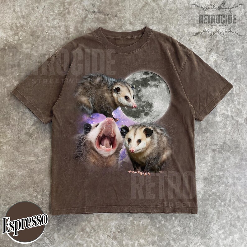 May include: Espresso-coloured t-shirt with a graphic of three opossums and a full moon. The opossums are in various poses, one yawning. The shirt has a vintage, distressed appearance. The word "RETROCIDE" is printed on the shirt.
