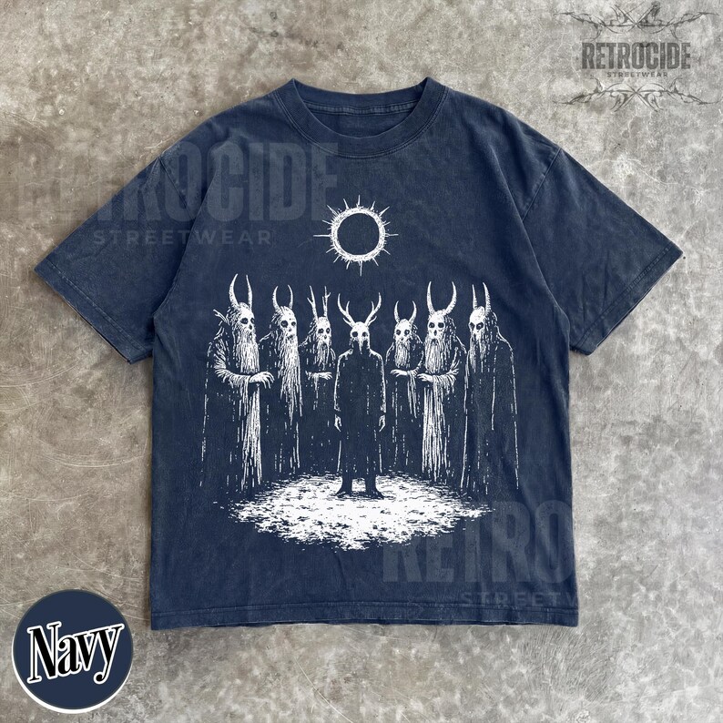 May include: Navy blue t-shirt with a white graphic of figures with horned masks and a sun. The shirt has the text "RETROCIDE STREETWEAR" and the word "Navy" in a circle.