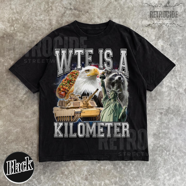 May include: Black t-shirt with a graphic design featuring a hot dog, bald eagle, tank, raccoon, and the Statue of Liberty. The text on the shirt reads "WTF IS A KILOMETER". The shirt has a vintage, distressed look.
