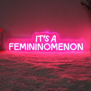 Peut inclure: Enseigne au néon rose avec le texte "It's a femininomenon".