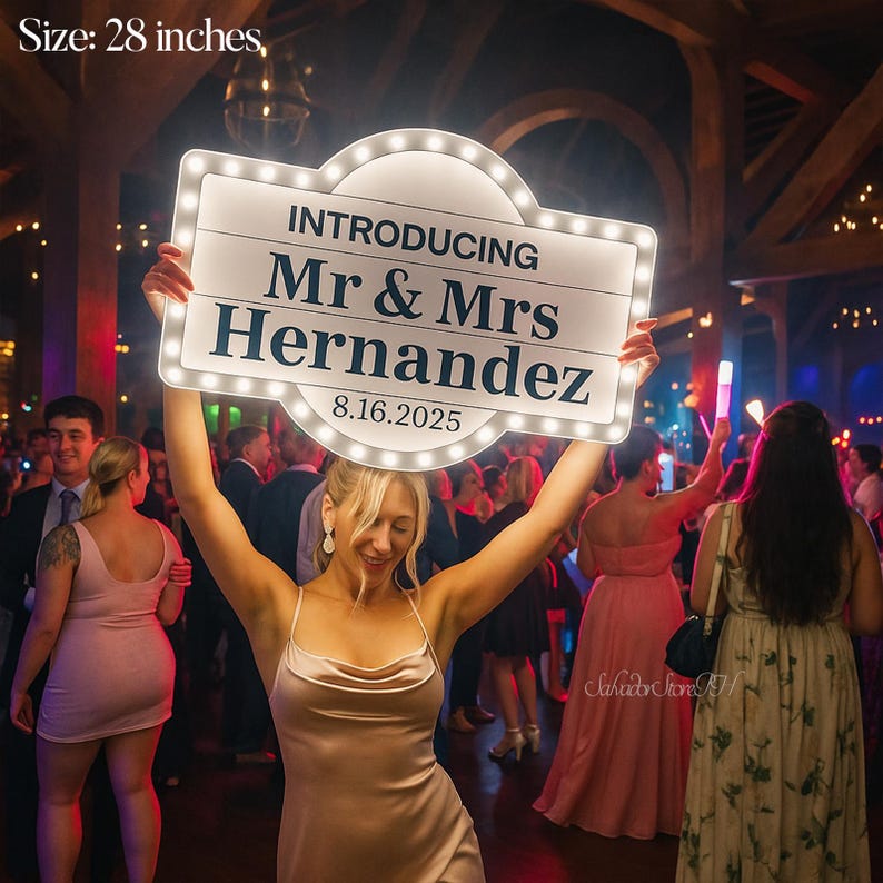 K&ouml;nnte beinhalten: Ein beleuchtetes Schild, 71 cm gro&szlig;, wird auf einer Hochzeitsfeier hochgehalten. Auf dem Schild steht "INTRODUCING Mr & Mrs Hernandez 8.16.2025" in einer klassischen Schriftart, umgeben von kleinen Lichtern. Der Hintergrund zeigt eine Menschenmenge.