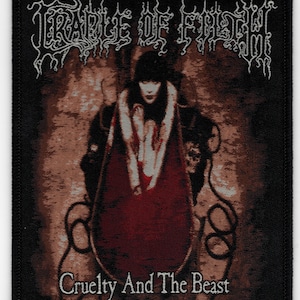 May include: Black patch featuring the band name "Cradle of Filth" in white, gothic-style lettering. The image depicts a figure in a red cloak, with the text "Cruelty And The Beast" below. The patch has a black border.