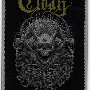 May include: Black and gold embroidered patch with the word "Cloak" in a gothic font. The patch features a skull with an eye in the center, surrounded by flames and a design of intertwined branches. The text "Black Flame Eternal" is at the bottom of the patch.