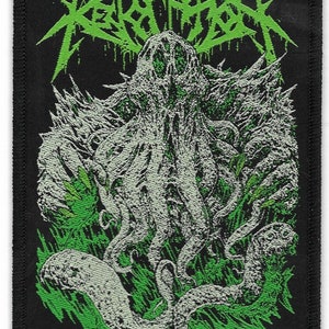 May include: Black and green embroidered patch with the text "REVOLUTION" in green and a white, tentacled creature with a gaping mouth.