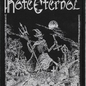 May include: Black and white embroidered patch with the text "Hate Eternal" in a gothic font. The patch features a skeletal figure holding a trident in a graveyard setting with a full moon in the background.
