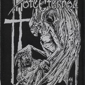May include: Black and white embroidered patch with the text "MORTCEREBRO" in a gothic font. The patch features a winged demon figure with a human-like face and a smaller figure with a hooded head.