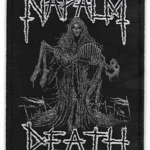 May include: Black and white embroidered patch with the text "NAPALM DEATH" in a gothic font. The patch features a skeletal figure in a hooded robe.