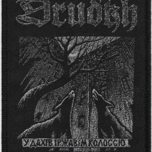 May include: Black and white embroidered patch with the text "Devoid" in a gothic font. The patch features a stylized image of two wolves howling at the moon in a forest setting. The text "SABBATH PRAXIS KOZMOS" is printed below the image.