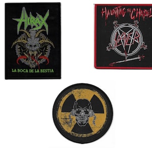 May include: Three black fabric patches with embroidered designs. The first patch features a green and black monster with the text "AIRAX LA BOCA DE LA BESTIA". The second patch features a red and white circle with the text "HAUNTING THE CHAPEL SLAYER". The third patch features a yellow and black radiation symbol with a skull inside.