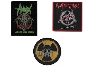 May include: Three black fabric patches with embroidered designs. The first patch features a green and black monster with the text "AIRAX LA BOCA DE LA BESTIA". The second patch features a red and white circle with the text "HAUNTING THE CHAPEL SLAYER". The third patch features a yellow and black radiation symbol with a skull inside.