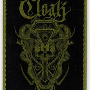 May include: A black and green embroidered patch with the word "Clack" in a gothic font. The patch features a skull with a cross and two snakes wrapped around a coffin.