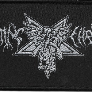 May include: A black embroidered patch with a white star and a winged figure in the center. The text "ROTTING CHRIST" is embroidered in white on either side of the star.