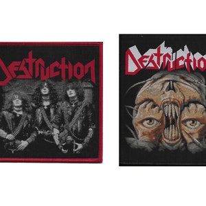 May include: Two black and red embroidered patches with the word "Destruction" in white lettering. The first patch features a band photo of three people. The second patch features a skull with a mouth open wide and eyes looking up.
