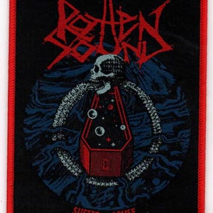 May include: A black and red embroidered patch with the band name "Rotten Sound" in red lettering. The patch features a skull with a coffin and the words "Suffer to Abuse" in red lettering.