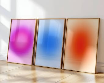 Op de afbeelding: Drie ingelijste abstracte kunstprints met een kleurverloop-effect. De prints zijn in een lichtroze, lichtblauw en lichtoranje kleur.