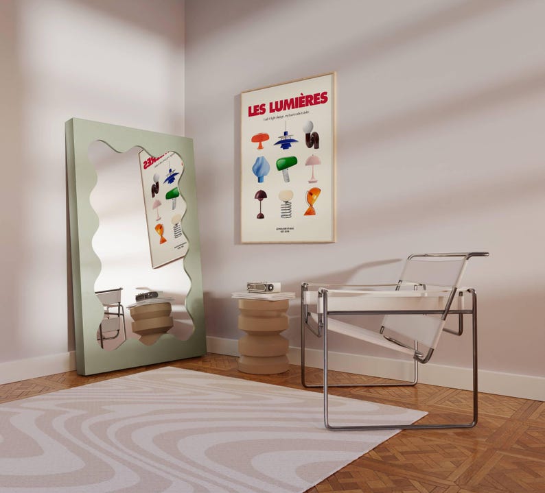 May include: A room interior featuring a large, wavy-edged, mint-green mirror and a framed poster with the text "LES LUMI&Egrave;RES". A clear chair and a beige side table are also visible. The room has a wooden floor and a patterned rug.