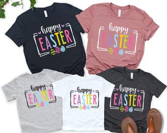 May include: A collection of short-sleeved t-shirts in various colors, each featuring the text "happy EASTER" in a colorful, framed design with Easter eggs. Colors include navy, pink, gray, white, and charcoal.