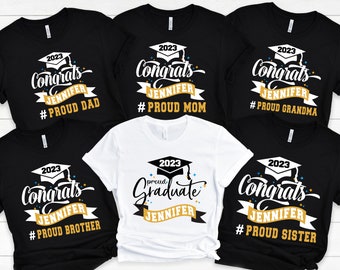 May include: Set of six black and white t-shirts with gold text and graphics. The shirts feature the text "Congrats Jennifer" and "Proud [Family Member]" with the year 2023. One shirt features the text "Proud Graduate Jennifer".