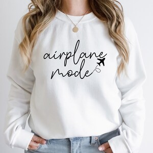 a woman wearing a white sweatshirt with the words airplane model printed on it