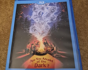 May include: A blue Blu-ray disc case with a dark image of a group of people around a campfire. The image has a ghostly figure above the campfire. The title of the movie is "Are You Afraid of the Dark?"