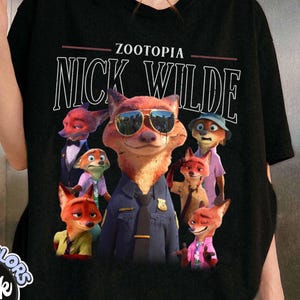 Puede incluir: Camiseta negra con el texto blanco "ZOOTOPIA NICK WILDE" sobre un gr&aacute;fico de Nick Wilde y otros personajes de zorro. Los zorros llevan gafas de sol, uniformes y ropa informal de la pel&iacute;cula animada.