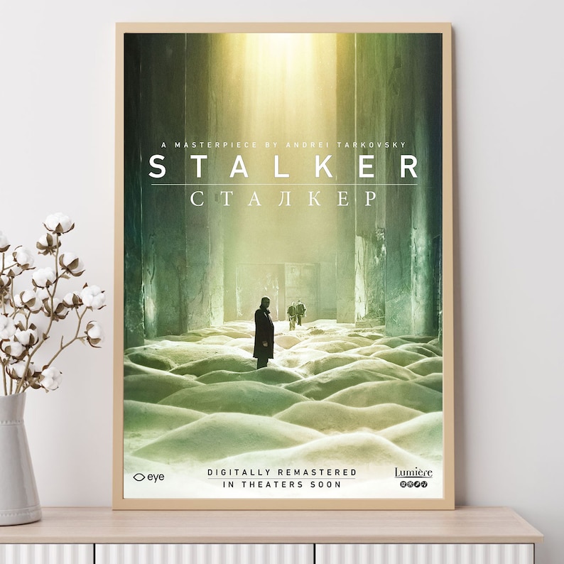 May include: A film poster for the movie "Stalker" by Andrei Tarkovsky. The poster shows a man in a trench coat standing in a barren, snowy landscape. The title of the film is written in both English and Russian. The poster also includes the text "Digitally Remastered" and "In Theaters Soon".
