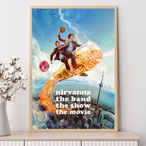 May include: A framed poster featuring a surreal scene with two men riding a bottle of orange liquid, with a cityscape in the background. The poster has the text "nirvanna the band the show the movie". The sky is blue with lightning.