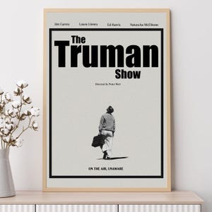 Könnte beinhalten: Ein Schwarzweiß-Filmplakat für den Film "The Truman Show" mit Jim Carrey, Laura Linney, Ed Harris und Natascha McElhone. Das Plakat zeigt den Titel des Films in großen Fettdruckbuchstaben und den Slogan "On the air, unaware".