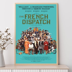 May include: A framed movie poster for "The French Dispatch" with a teal background. The poster features a large ensemble cast of characters and the film's title in large, illuminated letters. The text includes the film's tagline and release date.