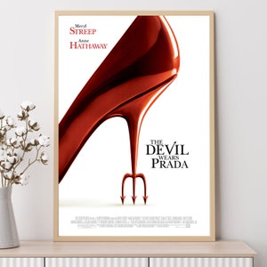 May include: Movie poster for "The Devil Wears Prada" featuring a red high heel shoe with a devil's pitchfork in the background. The poster also includes the names of the stars, Meryl Streep and Anne Hathaway.