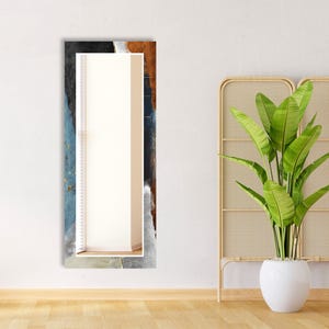 a plant in a white vase next to a mirror