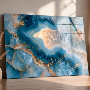 Könnte beinhalten: Ein rechteckiges Wandbild mit Hochglanzoberfläche und einem wirbelnden Achat-Steinmuster. Das Design zeigt tief dunkelblaue, hellblaue und durchscheinend weiße Schichten, die durchgehend mit metallischen Goldadern durchzogen sind.