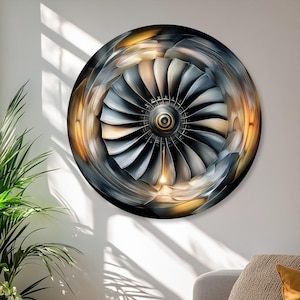 Könnte beinhalten: Ein kreisförmiges Wandbild mit einer detaillierten, kontrastreichen Illustration einer Strahltriebwerksturbine. Das Design zeigt metallisch silberne und dunkelgraue Lüfterschaufeln in radialer Anordnung, akzentuiert durch warme goldene Lichtreflexe.