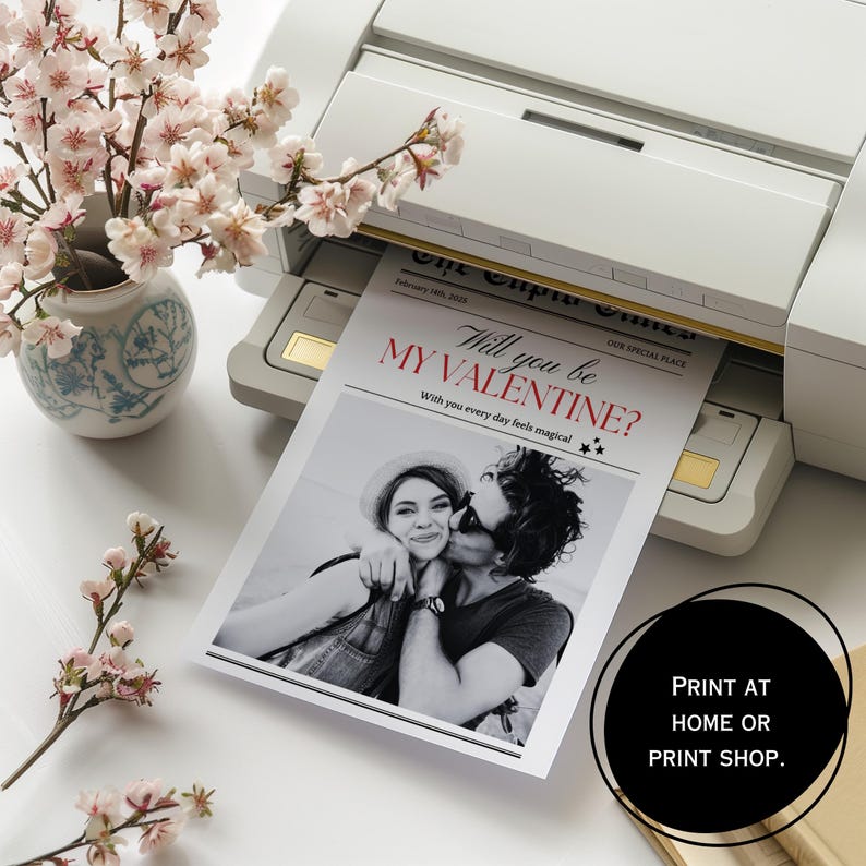 May include: A printable Valentine's Day card featuring a black and white photograph of a couple. The text on the card reads "Will you be my Valentine? With you every day feels magical." The card is being printed on a printer.