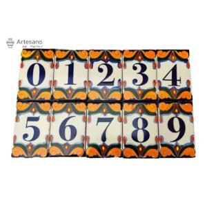May include: A collection of ten ceramic tiles, each featuring a number from 0 to 9. The numbers are in dark blue on a cream-coloured background. Each tile has a decorative border with orange, blue, and green accents. The tiles are from Artesano de Mexico.