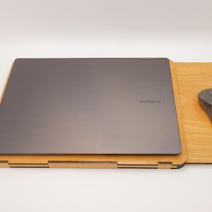 May include: A wooden laptop stand with a built-in mouse pad. A gray laptop is on the stand and a gray wireless mouse is on the mouse pad.