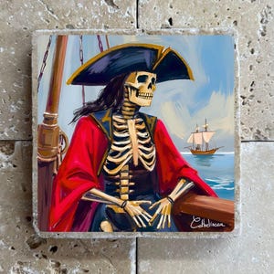 Op de afbeelding: Vierkant kunstwerk met een skeletpiraat op een schip, met een steekhoed en een rode jas. Een schip zeilt op de achtergrond op een blauwe zee onder een bewolkte hemel. Het kunstwerk is gesigneerd door de kunstenaar.