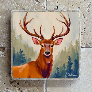 Peut inclure: Œuvre d'art carrée représentant un cerf majestueux avec de grands bois, peint dans des tons d'orange, de brun et de rouge. Le cerf se détache sur un fond de forêt avec des arbres verts et bleus. L'œuvre est signée "Cathelincau".