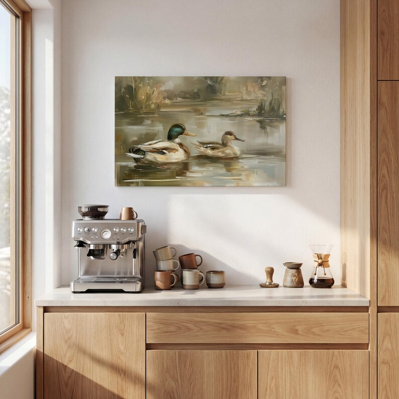 a kitchen counter with a coffee machine, coffee cups, and a painting of ducks swimming in a pond.