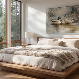 a serene bedroom scene with a large bed, a painting of ducks on the wall, and a window overlooking a wooded area.