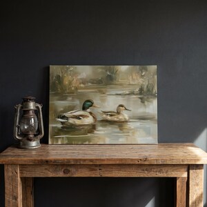 a painting of two ducks swimming in a pond, displayed on a wooden table.